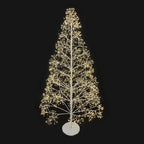 Sapin lumineux blanc en métal de 180 cm devant une porte en bois ancien, avec un pouf tricoté et un tapis en fausse fourrure blanche