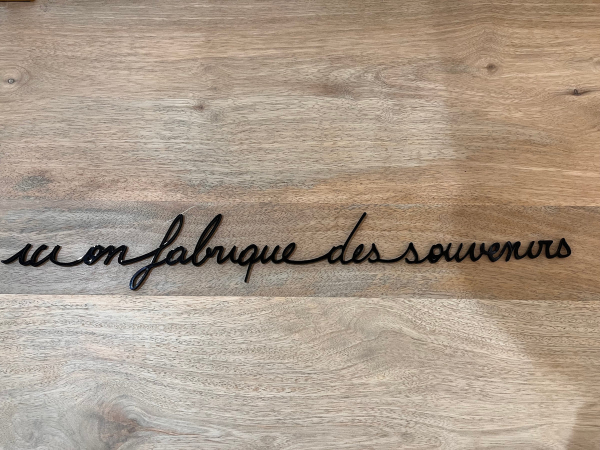 Phrase murale « Ici on fabrique des souvenirs » noire en plexiglas recyclé, sans clou ni trou – Atelier Suspendu